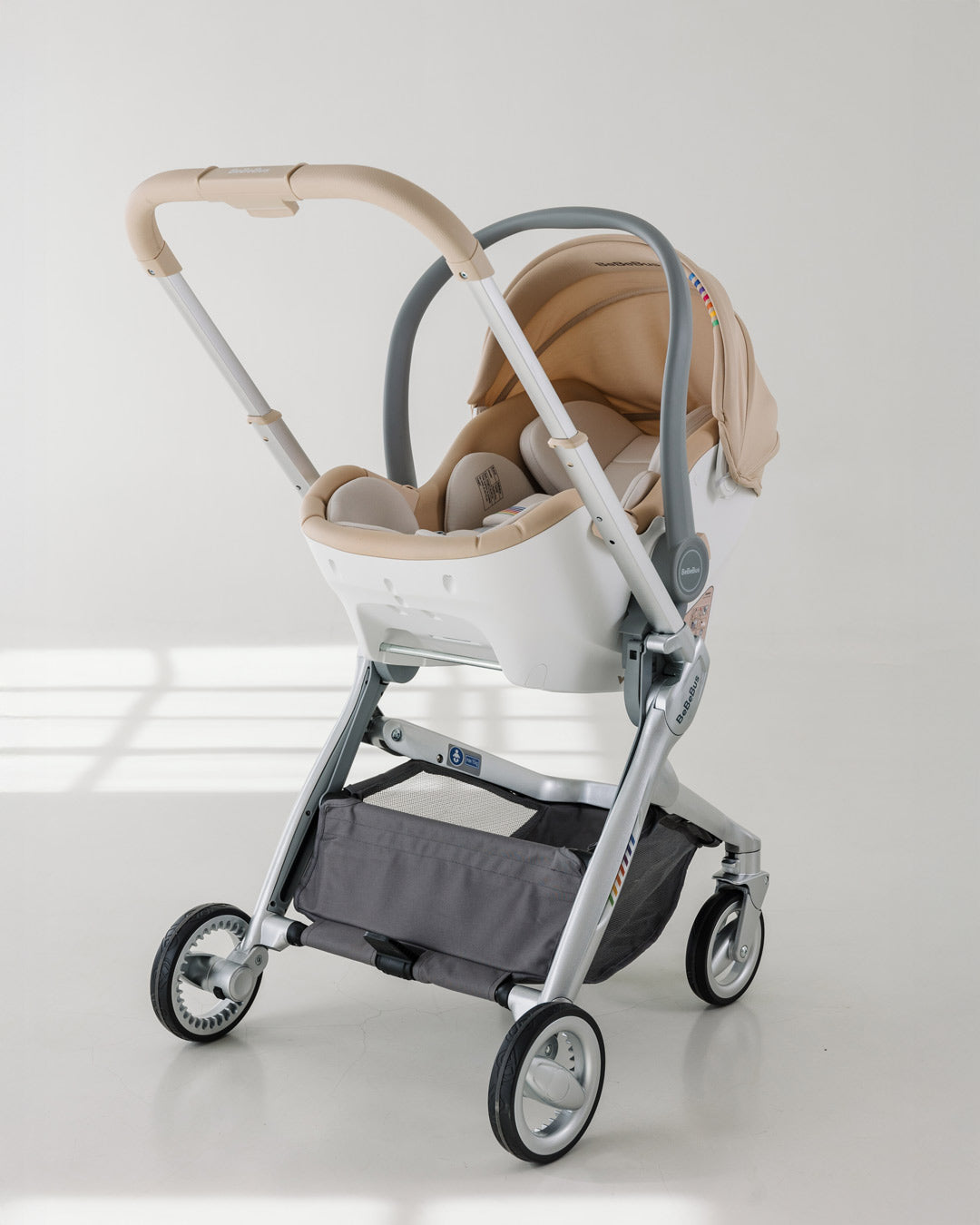 BeBeBus Guard Infant Car Seat attached to a stroller frame in a bright, minimalist room, showcasing the padded insert and canopy.