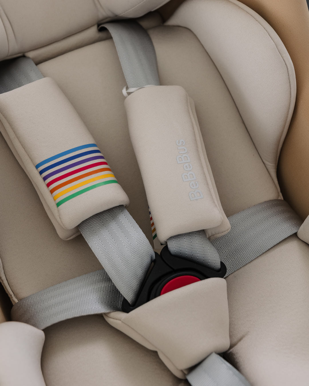 Close-up of the BeBeBus Guard Car Seat harness system with grey straps and rainbow-accented padded covers.