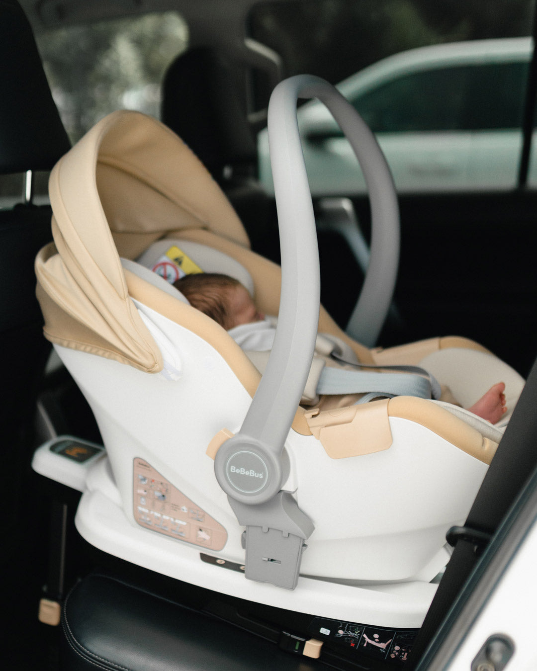Newborn safely secured in the BeBeBus Guard baby car seat, rear-facing inside a vehicle with ISOFIX base installed.