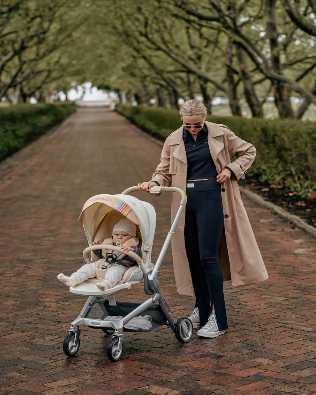 Mom pushing BeBeBus Art+ PRO Stroller on brick path, showing shock-absorbing wheels and ergonomic handle perfect for all terrains.