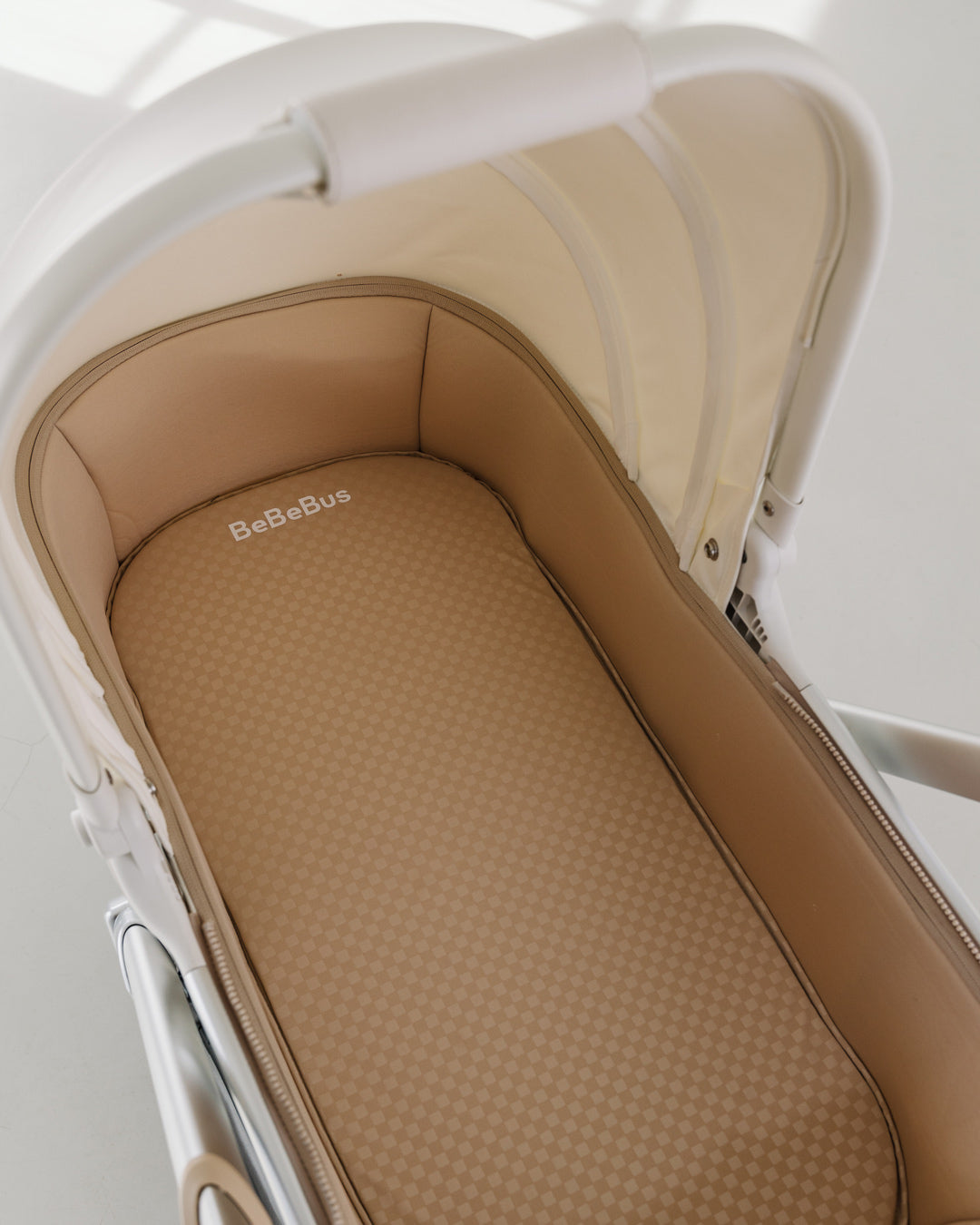Interior of BeBeBus Bassinet featuring soft check-pattern mattress for baby comfort.