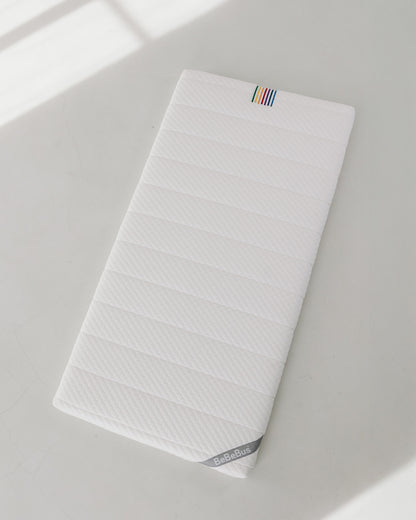 Full view of BeBeBus newborn-to-toddler mattress on a clean white surface, showcasing its flat, breathable design.