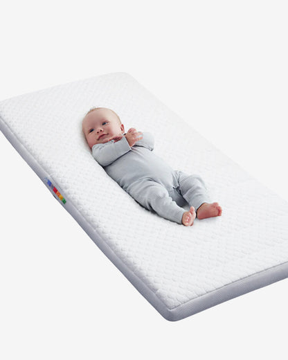 Baby lying comfortably on the BeBeBus infant mattress with quilted support and soft breathable cover.