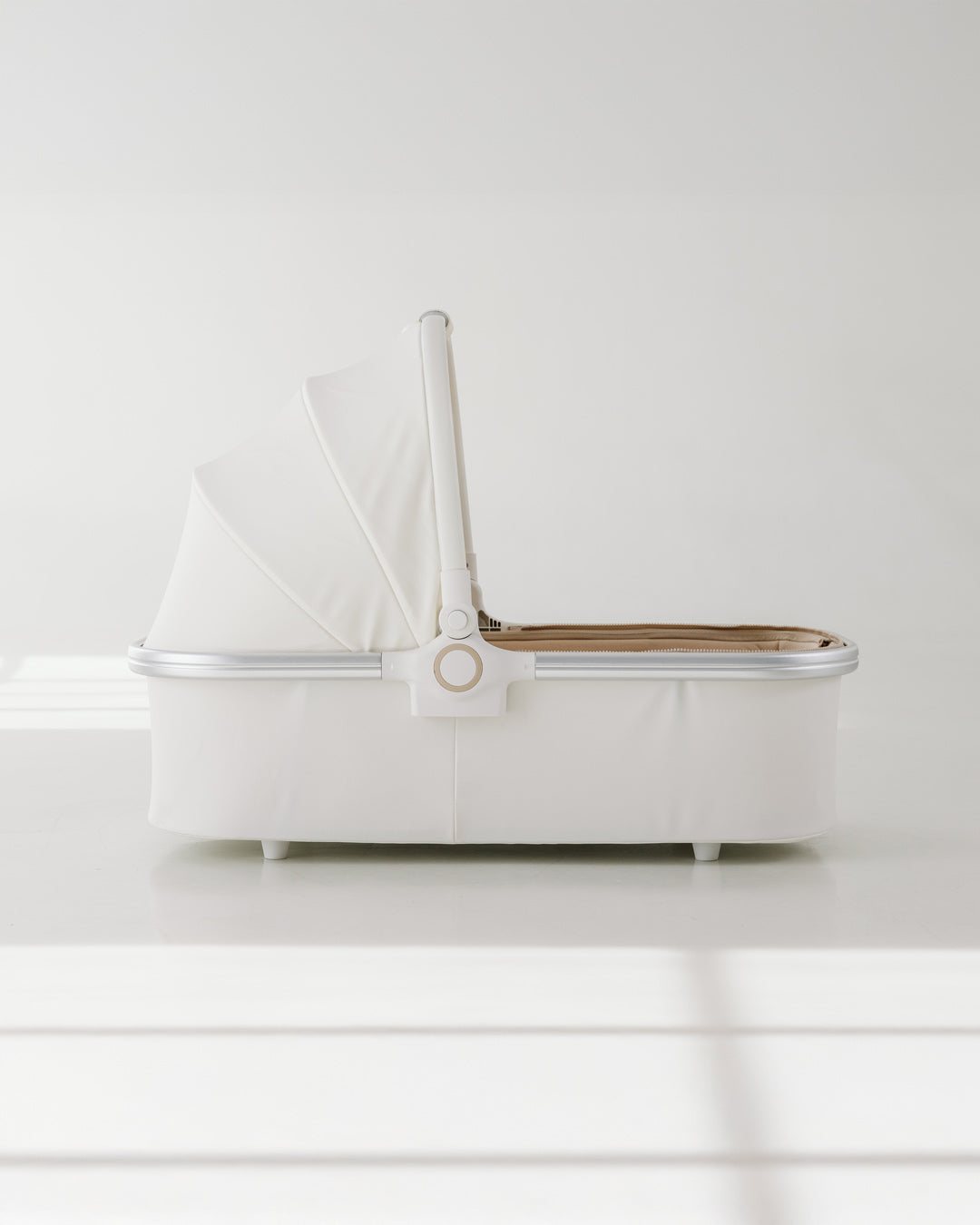 Side view of BeBeBus Bassinet in neutral tones, showing foldable sun canopy and compact design.