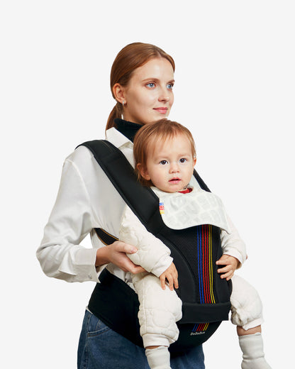 Woman carrying a baby in a black baby carrier with colorful accents on a white background